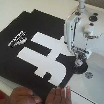 Appliqué logo being stitched onto black fabric at the sewing machine